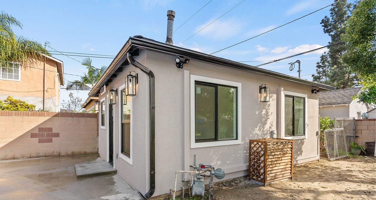 Light stucco Hillstar-built ADU side elevation with black window trim — completed project