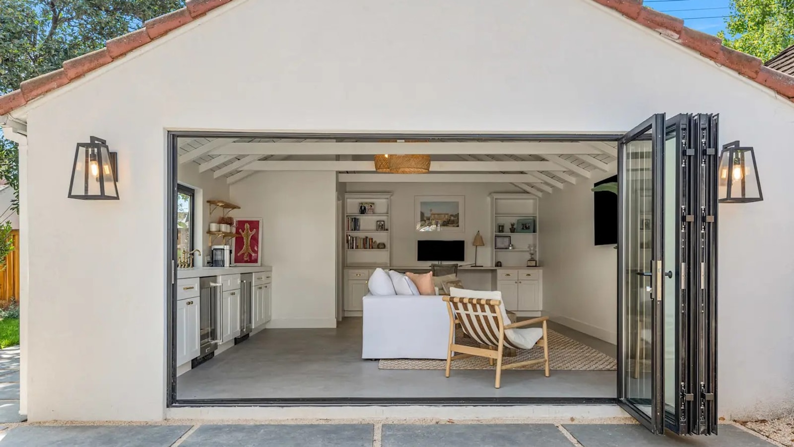 Detached garage with bifold glass doors open showing finished living space inside