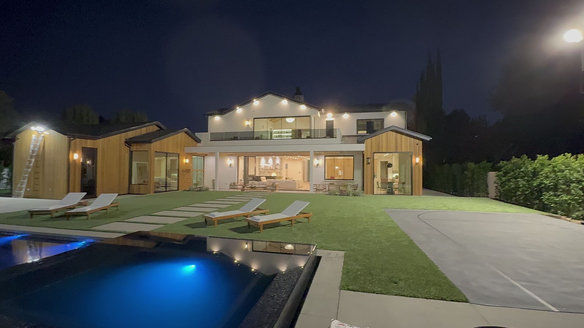 Luxury modern backyard with pool and lit home at night