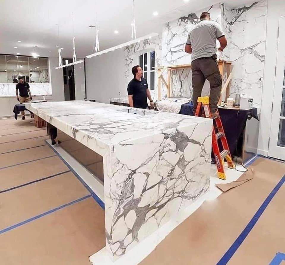 Construction crew installing marble slab kitchen island