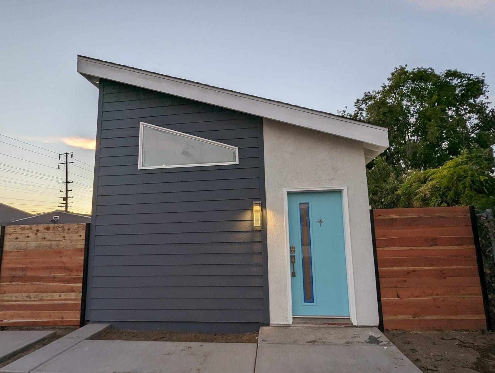 Completed ADU by Hillstar Construction Inc at dusk with shed roof and blue entry door