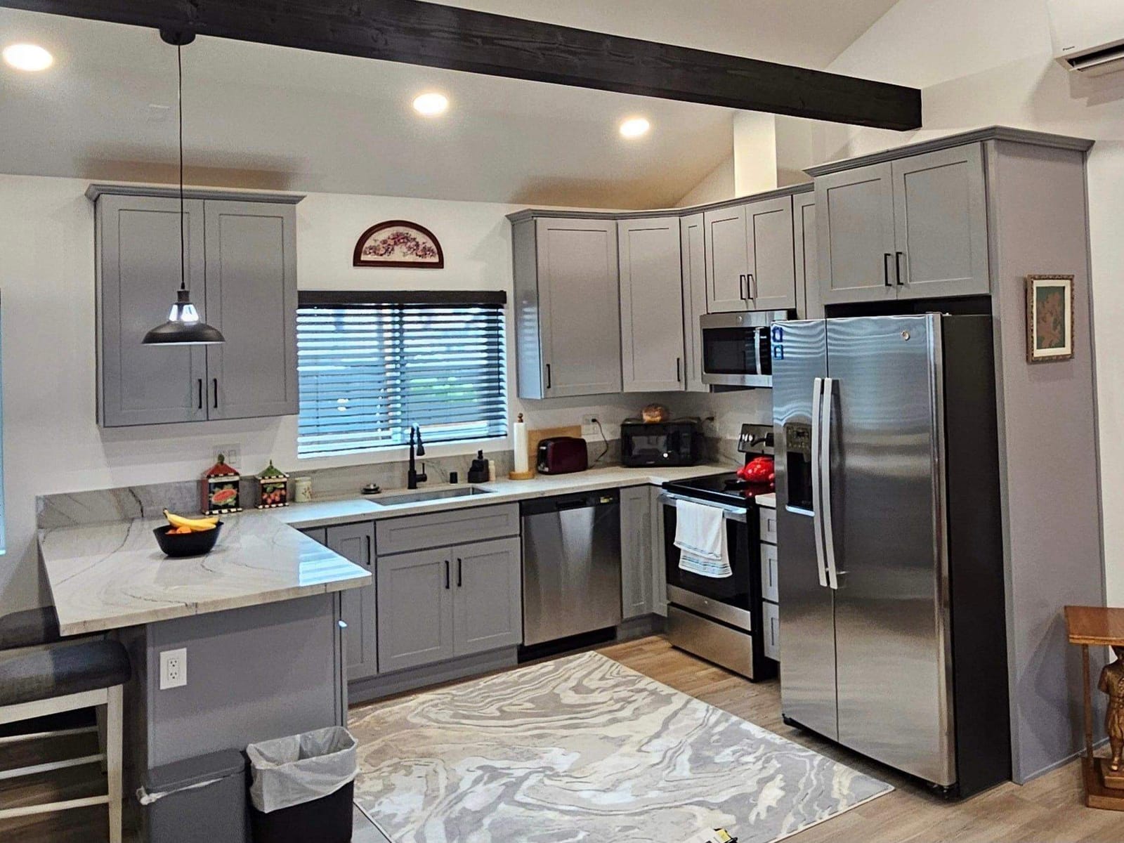 Finished kitchen by Hillstar Construction Inc with grey shaker cabinets and stainless appliances