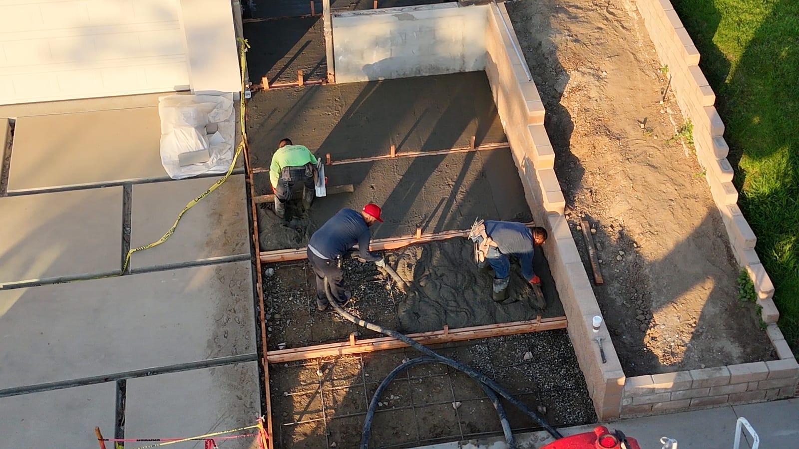 Aerial view of a concrete crew placing a driveway pour from a pump hose and screeding it to the forms