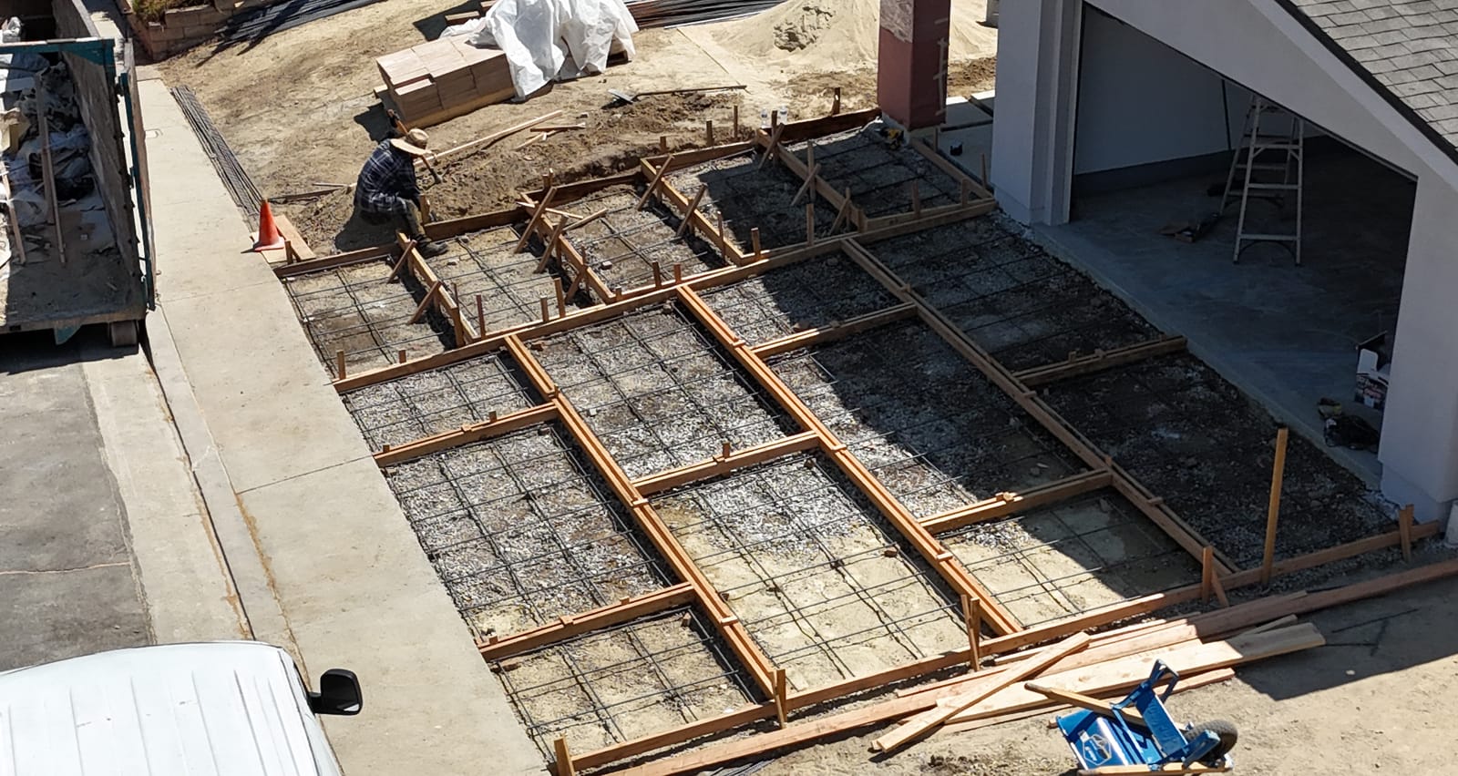 Aerial view of driveway prep before a concrete pour: wood forms set and a rebar grid tied over the base