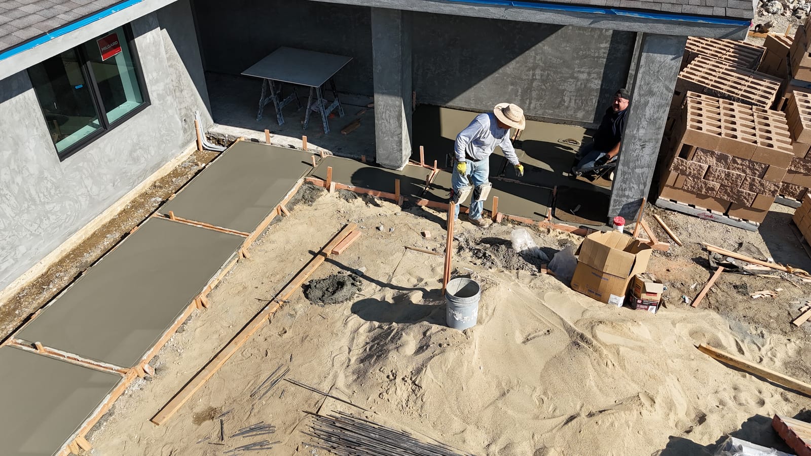Aerial view of a slab pour beside an existing home on a Hillstar Construction Inc jobsite